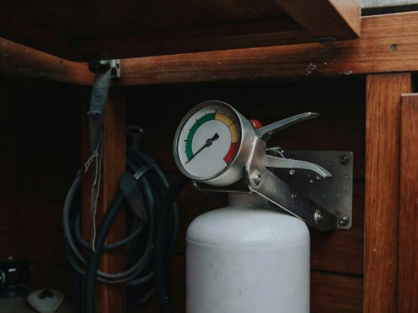 Close-up of a pressure gauge in the green zone on a marine fire extinguisher mounted in a cockpit locker
